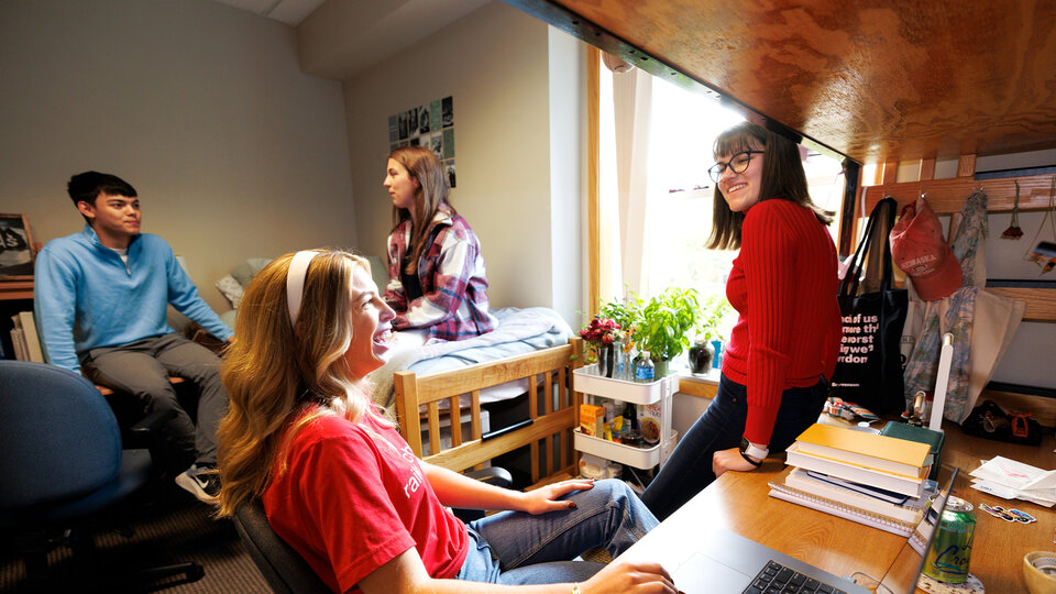 A group of students sitting and talking in a dorm room
